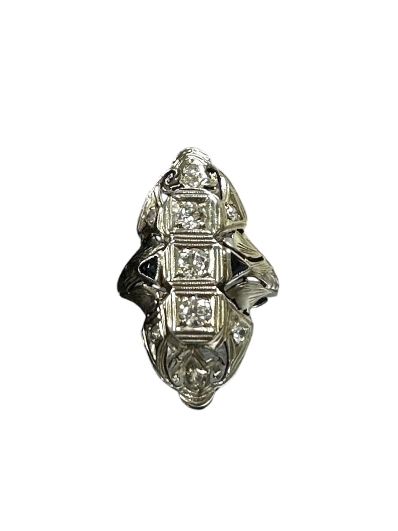 Pu&ograve; includere: Un anello d'argento con un design delicato che presenta una fila di cinque diamanti a taglio cuscino incastonati in un motivo geometrico.