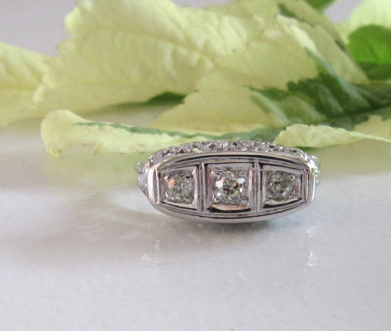 May include: A silver ring with three square-shaped diamonds set in a decorative band.