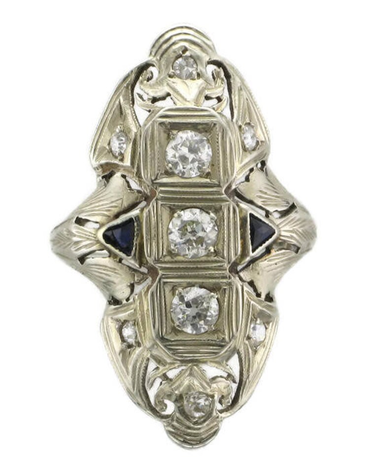Pu&ograve; includere: Un anello vintage con un design a filigrana che presenta un gruppo centrale di diamanti e due pietre di zaffiro pi&ugrave; piccole.