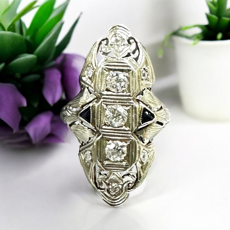 Pu&ograve; includere: Un anello d'argento con un design geometrico che presenta pi&ugrave; diamanti rotondi e accenti neri.