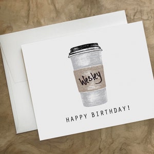 May include: A white card with a black and white illustration of a coffee cup with a brown paper sleeve that says "Wesley" on it. The text "Happy Birthday!" is printed below the cup.