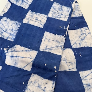 May include: A folded piece of fabric featuring a blue and white chequered pattern. The design consists of solid blue squares alternating with white squares that have a subtle, crackled, or marbled texture, creating a distinct visual contrast.