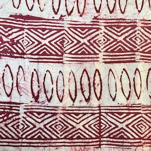 Peut inclure: Gros plan sur un tissu avec un motif répétitif bordeaux et blanc. Le motif comprend des formes géométriques comme des losanges et des ovales, créant une esthétique tribale texturée. Le tissu semble fait à la main.