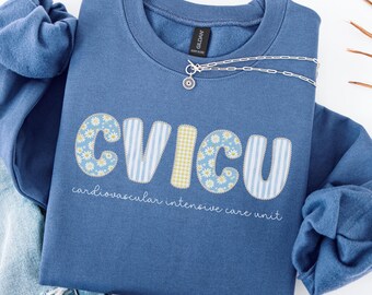 May include: An indigo blue crewneck sweatshirt featuring the text CVICU in a patterned applique font, with the words cardiovascular intensive care unit printed below in white, paired with distressed blue denim jeans.