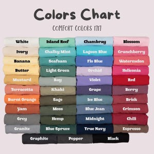 Puede incluir: Una carta de colores para camisetas Comfort Colors 1717, que muestra una cuadr&iacute;cula de muestras de tela dobladas en varios tonos. Cada muestra est&aacute; etiquetada con su nombre de color espec&iacute;fico, desde blanco, amarillo y naranja hasta verde, azul, rosa, rojo y negro.