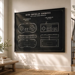 May include: A framed black print titled "Retro Controller Schematics" with white diagrams of 8-bit and 16-bit classic controllers. The print is displayed on a white wall in a well-lit room with a wooden bench and a plant.