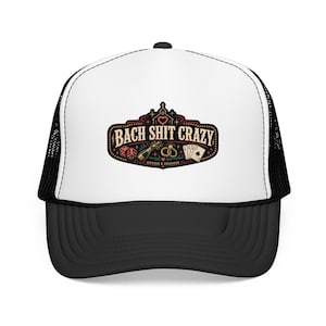 May include: A black and white trucker hat with a curved brim. The front panel is white with a graphic that reads "Bach Shit Crazy" with illustrations of dice, champagne, rings, and playing cards. The hat has a mesh back.