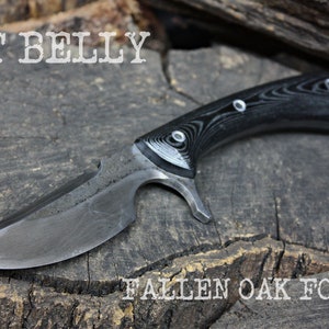 May include: A black and silver knife with a wooden handle. The knife has a curved blade and a small hole in the handle. The knife is on a wooden surface. The text "POT BELLY" and "FALLEN OAK FORGE" are visible in the image.