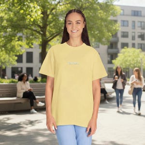 May include: A pale yellow short-sleeved t-shirt featuring the text "Talk later." embroidered in small white letters on the centre of the chest. The garment has a crew neckline and a relaxed fit, constructed from a solid-coloured fabric.