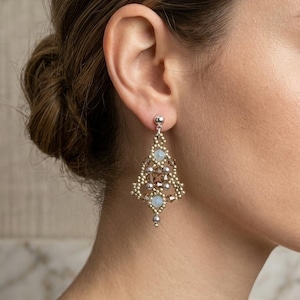 May include: A dangling earring featuring a triangular beaded design in gold, brown, and silver tones. The piece incorporates small metallic beads, faceted brown crystals, and two pale blue cabochon stones, finished with a silver-toned stud post.