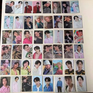 以下が含まれることがあります： 様々なポーズや服装の個人が写った長方形の写真カードのコレクション。カードは、ピンク、赤、青、ニュートラルな色合いなど、さまざまな色を示しています。画像はグリッドのようなパターンで配置されています。