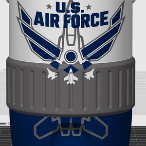 May include: A cylindrical white and blue cooler featuring the U.S. Air Force logo in dark blue text with a stylized aircraft graphic. The middle section has a textured gray band, and the lower blue portion displays a faint gray aircraft outline.