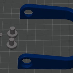 May include: A dark blue U-shaped bracket with circular holes at each end, accompanied by two small gray cylindrical pegs and one gray component featuring a circular base, a raised center, and a small angled protrusion extending from the side.
