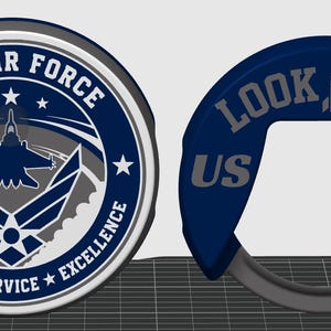 May include: A circular U.S. Air Force emblem featuring a central aircraft silhouette, stars, and the text Integrity, Service, Excellence. Beside it is a dark blue, C-shaped object with the text LOOK UP! and US AF, featuring a rocket icon.