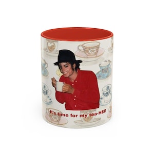 May include: A white ceramic mug with a red interior and rim, featuring a repeating pattern of various teacups on saucers. In the center, a person in a black fedora and red shirt holds a white mug. The text reads, It's time for my tea-HEE.