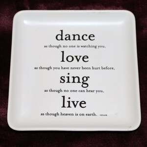 Op de afbeelding: Een vierkant wit keramieken dienblad met afgeronde hoeken en zwarte bedrukte tekst: dance as though no one is watching you, love as though you have never been hurt before, sing as though no one can hear you, live as though heaven is on earth.