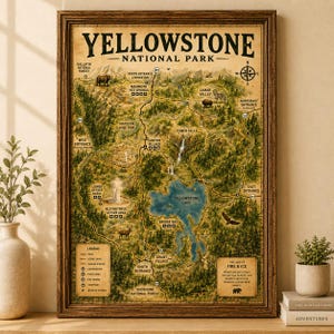 May include: A framed vintage-style map of Yellowstone National Park with a dark wood frame. The map features detailed topography, roads, landmarks like Yellowstone Lake, and illustrations of wildlife including a bear, elk, and eagle.