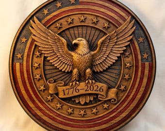 May include: A circular wooden wall plaque featuring a carved bald eagle with wings spread wide. The background displays a stained American flag pattern with stars and stripes. A banner across the eagle's talons displays the text 1776-2026.