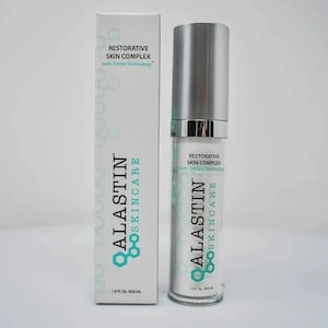 Op de afbeelding: Een witte doos en een heldere fles van Alastin Skincare Restorative Skin Complex. De doos en de fles hebben hetzelfde ontwerp, met de merknaam en productinformatie in zwart en blauwgroen. De fles bevat 29,6 ml.