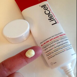 May include: A white and red tube of LifeCell South Beach Skincare All-In-One Anti-Aging Treatment with a detached white cap. The tube features text detailing benefits like anti-wrinkle and hydration, with a net volume of 75 ml printed on it.