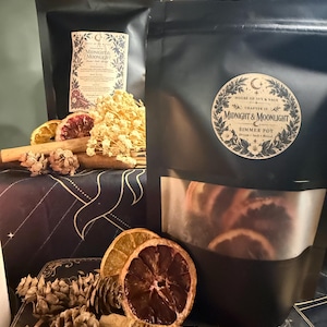 May include: Two black stand-up pouches labelled House of Ivy & Sage Chapter IV Midnight & Moonlight Simmer Pot. The pouches feature a clear window revealing dried citrus slices, cinnamon sticks, and pinecones arranged in the foreground.