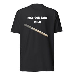 May include: Black t-shirt with the text "MAY CONTAIN MILK" in white, above an image of a metal file. The shirt is a short-sleeved crew neck.
