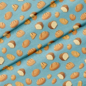 May include: A light blue fabric featuring a repeating pattern of various golden-brown bread loaves and rolls. The design includes whole round loaves, oval-shaped breads, and sliced pieces, all scattered across the surface in a consistent print.