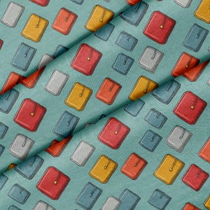 Puede incluir: Una tela de color verde azulado con un patrón repetitivo de pequeños objetos rectangulares similares a carteras en tonos rojo, amarillo, azul y gris. Cada objeto está orientado verticalmente e incluye un detalle circular dorado centrado.