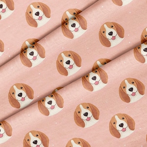 May include: A light pink fabric featuring a repeating pattern of beagle dog faces. Each dog illustration shows brown and white fur, a black nose, and a pink tongue sticking out. Small white dots are scattered across the pink background.