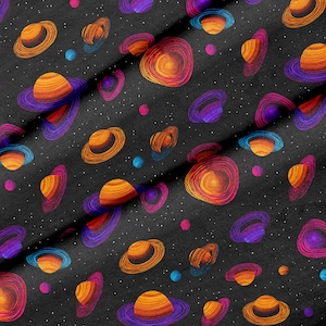 Puede incluir: Una tela negra con un patrón repetitivo de planetas naranjas y amarillos con anillos morados, intercalados con pequeños puntos blancos que representan estrellas. El diseño crea una densa escena cósmica en toda la superficie.