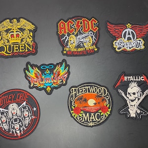 May include: A collection of seven embroidered band patches featuring logos and imagery for Queen, AC/DC, Aerosmith, Journey, Mötley Crüe, Fleetwood Mac, and Metallica. Each patch displays colorful thread work, band names, and iconic rock music graphics.
