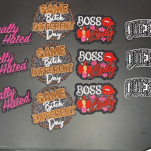 May include: A collection of embroidered patches featuring three designs: pink text reading Locally Hated, circular patches with gold and white text reading Same Bitch Different Day, and patches with Boss Lady text, red lips, and crowns, plus black and white Queens text.