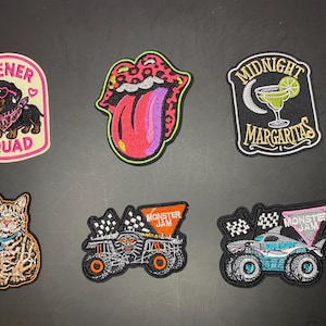 Peut inclure: Six écussons brodés représentant un teckel avec des lunettes roses et le texte WIENER SQUAD, une bouche à motif léopard avec une langue, un verre à margarita avec le texte MIDNIGHT MARGARITAS, un chat tigré et deux camions Monster Jam.