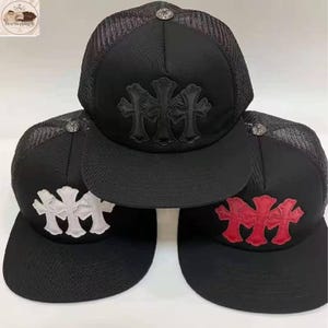 Puede incluir: Gorras de camionero negras con diseños de cruces en negro, blanco y rojo. Cada gorra tiene una parte trasera de malla y una visera curva. Las gorras tienen un botón plateado en la parte superior.