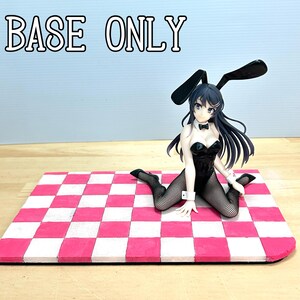 以下が含まれることがあります： 黒いバニーガールの衣装を着た女性のフィギュア。長い黒髪、網タイツ、ウサギの耳があり、ピンクと白のチェック柄のベースにひざまずいています。「BASE ONLY」の文字が上にあります。