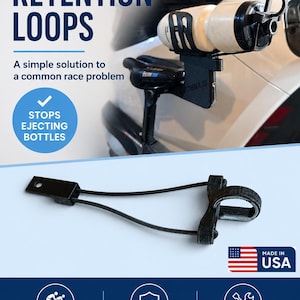 May include: A black bottle retention loop featuring a mounting bracket, two thin elastic cords, and a textured circular strap. The text reads BOTTLE RETENTION LOOPS, A simple solution to a common race problem, STOPS EJECTING BOTTLES, MADE IN USA, TRIATHLON TESTED, SECURE FIT, EASY TO INSTALL, FOCUS ON YOUR RACE. WE'LL KEEP YOUR BOTTLE IN PLACE.
