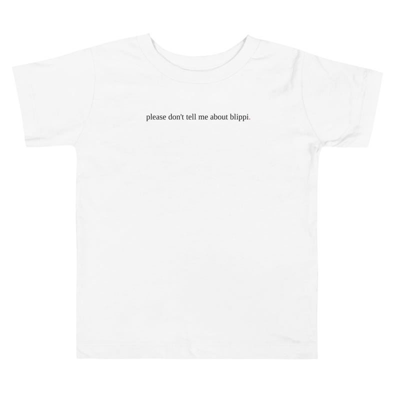 May include: White toddler t-shirt with the phrase "please don't tell me about blippi." printed in black, centered on the front. The shirt has short sleeves and a crew neck.