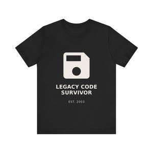 May include: Black t-shirt with a white graphic of a floppy disk and the text "LEGACY CODE SURVIVOR EST. 2003". The shirt is made of a soft material and has a crew neck.