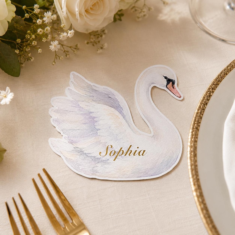 May include: A die-cut paper place card shaped like a swan with watercolor-style white and soft grey feathers, a black and orange beak, and the name Sophia printed in gold script lettering across the center of the swan's body.