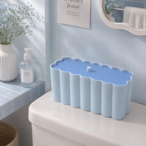 May include: A rectangular storage box with a scalloped edge design in light blue. The box features a matching light blue lid with a small central knob. The sides of the container have a vertical, fluted texture, creating a consistent, repeating pattern around the entire exterior of the storage unit.