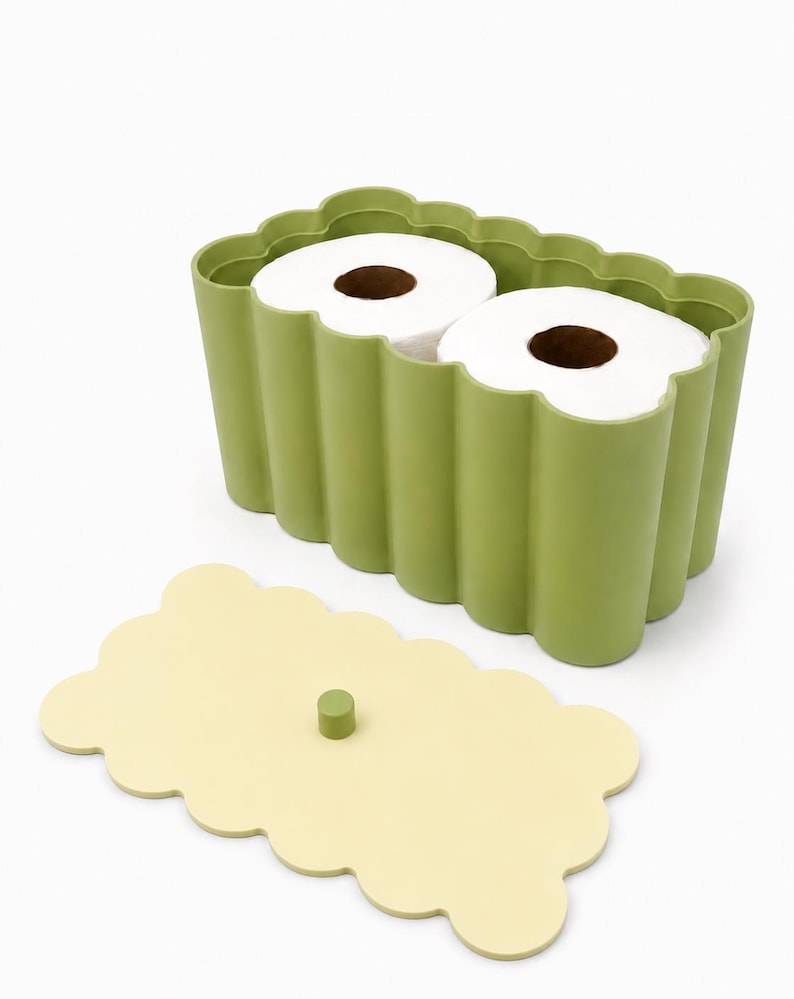May include: A sage green rectangular storage container with a scalloped edge design, holding two rolls of white toilet paper. The container includes a separate, flat, pale yellow lid with a small, centered sage green cylindrical knob handle.