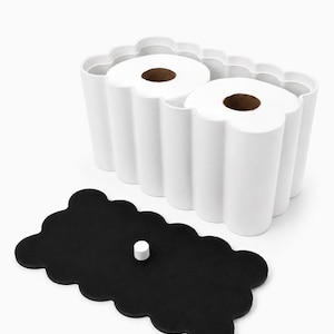 May include: A white, scalloped-edge rectangular container holding two rolls of white toilet paper, accompanied by a separate black, scalloped-edge lid featuring a small, centered white cylindrical knob for easy removal and placement.