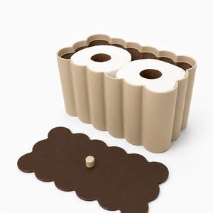 May include: A beige, scalloped-edge rectangular storage container holding two white toilet paper rolls. The container features a matching dark brown, scalloped-edge lid with a small, centered cylindrical knob for easy removal and access.