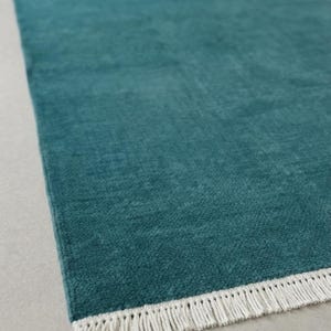 Handmade solid Indian Teal hand-knotted wool rug in modern living room.