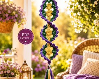 May include: A vertical hanging crochet decoration featuring three repeating floral motifs in yellow, green, and purple yarn. The design includes a central yellow flower column surrounded by green and purple scalloped edges, finished with a multi-colored tassel.