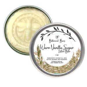May include: A round tin container with a white label that reads "Botanical Bars Warm Vanilla Sugar Lotion Bar 1 OZ INGREDIENTS: COCONUT OIL, SHEA BUTTER, BEESWAX, AND FRAGRANCE BOTANICAL BARS INC LAKE TOXAWAY, NC 28747". The tin is filled with a white lotion bar.