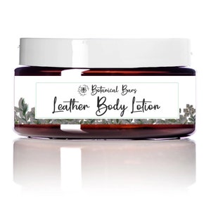 May include: A jar of Leather Body Lotion with a white lid and a label featuring the text "Leather Body Lotion" and "Botanical Bars". The label is decorated with green botanical illustrations. The jar is brown and sits on a white surface.