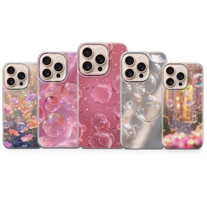 Può includere: Cinque custodie per telefono con vari design. Le custodie presentano immagini di bolle, fiori e un paesaggio da sogno. Le custodie sono in tonalità di rosa, trasparente e oro, offrendo una gamma di opzioni estetiche.
