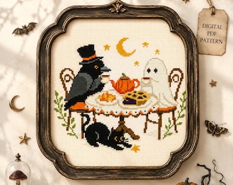 May include: A cross-stitch pattern in a dark ornate frame featuring a crow in a top hat and a ghost sitting at a table with a teapot and pie, with a black cat below. The design includes a yellow crescent moon and stars on cream fabric.