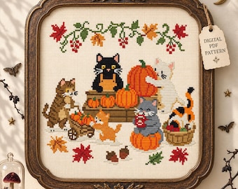 May include: A framed cross-stitch embroidery featuring five cats in an autumn harvest scene with pumpkins, a wheelbarrow, and falling leaves. A tag attached to the top right corner reads DIGITAL PDF PATTERN. The frame is dark brown with floral accents.